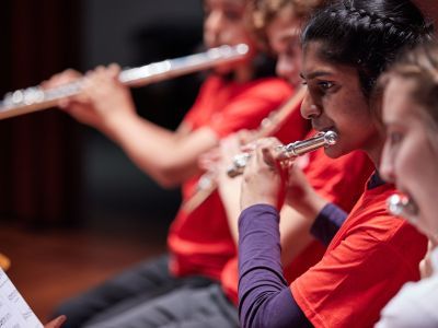 Four students play flutes in a line